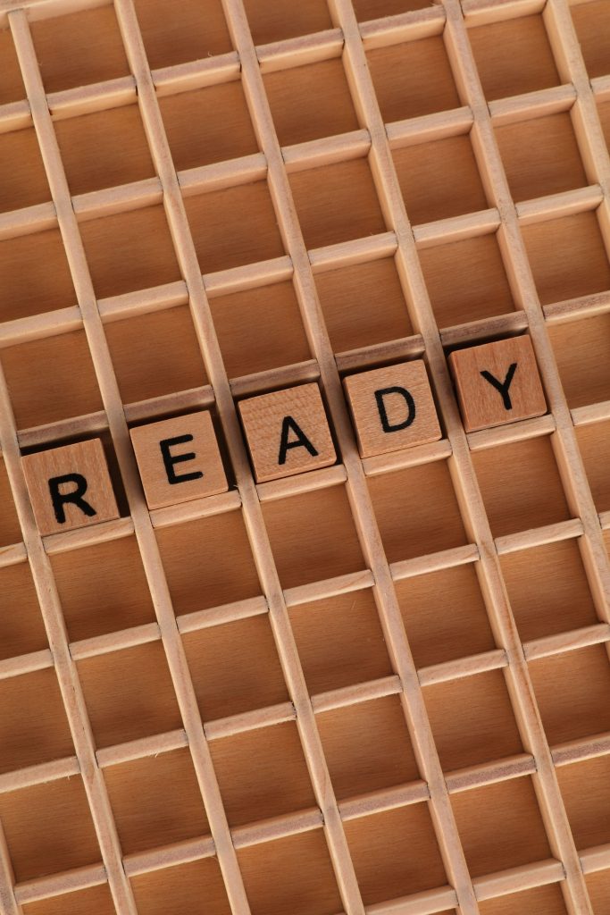 Wooden Scrabble tiles spelling 'READY' on a grid background. Perfect for motivational themes.